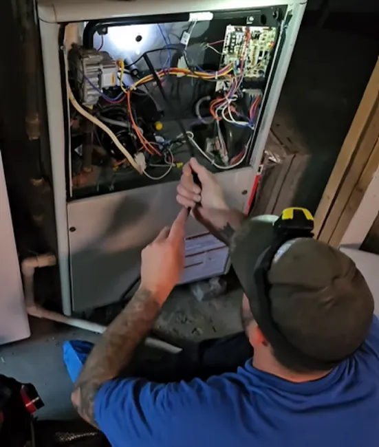 Technician repairing electrical panel with exposed wires and circuit components