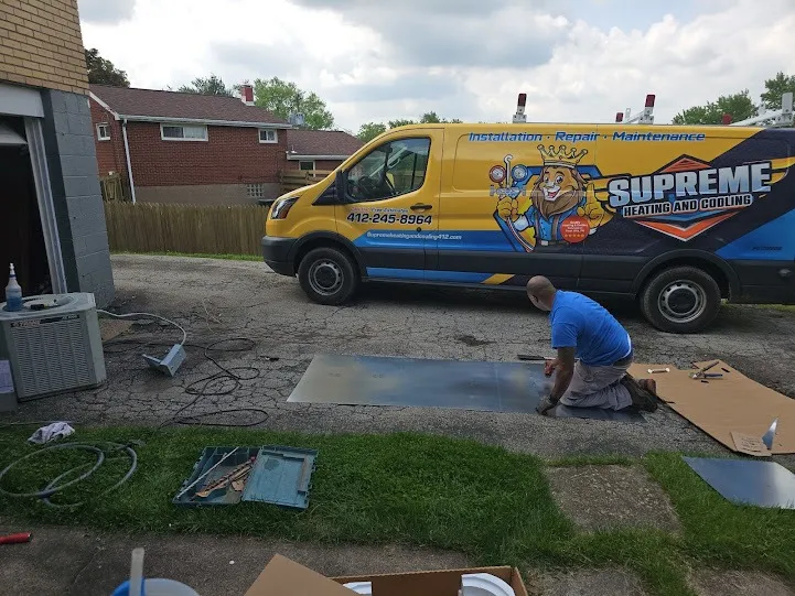 Yellow Supreme Heating and Cooling van with technician working outside