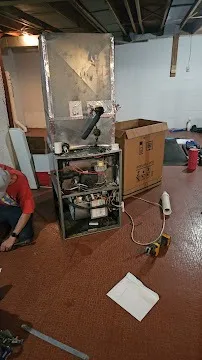 Old furnace and cardboard box in cluttered basement with concrete floor