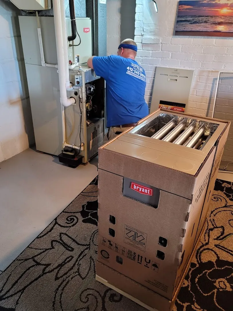 Technician installing Bryant HVAC system in mechanical room with equipment box