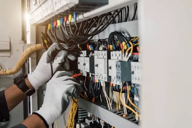 Electrician working on electrical panel with colorful wires and circuit breakers