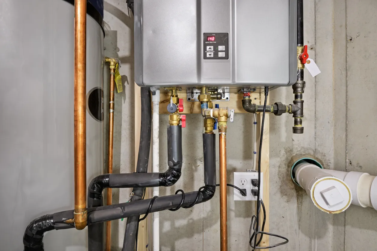 Tankless water heater with copper pipes and valves installed on concrete wall
