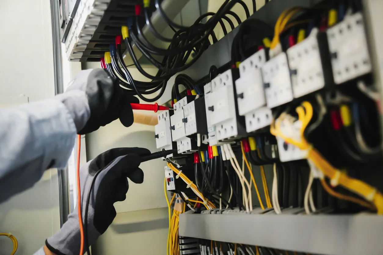 Electrician working on electrical panel with colorful wires and circuit breakers
