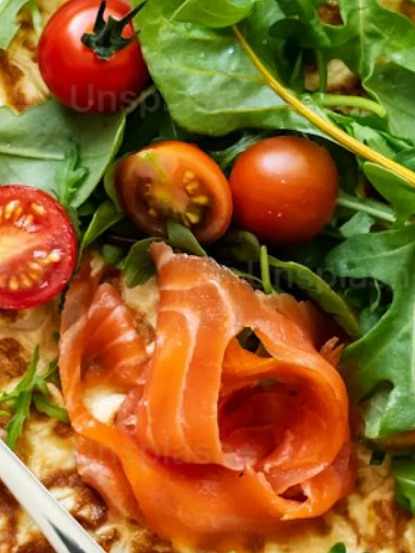 Smoked salmon slices with cherry tomatoes and fresh green leafy salad on a flatbread.
