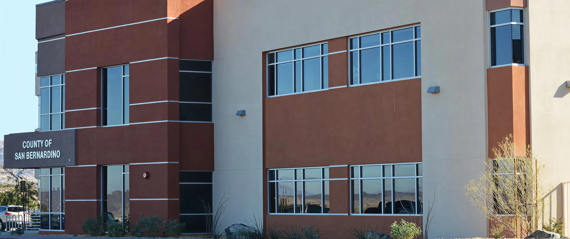 Modern two-story building with brown and beige exterior, with a sign reading 'County of San Bernardino'.