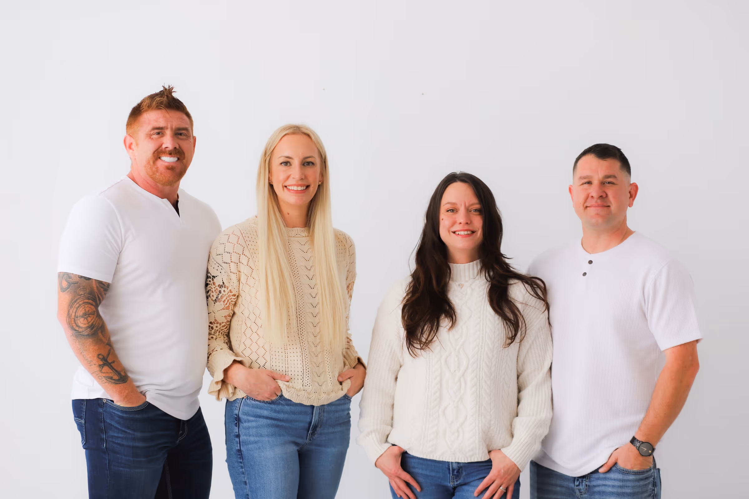 Roofing by Prodigy - Group of two men and two women standing against a white background, smiling at the camera.