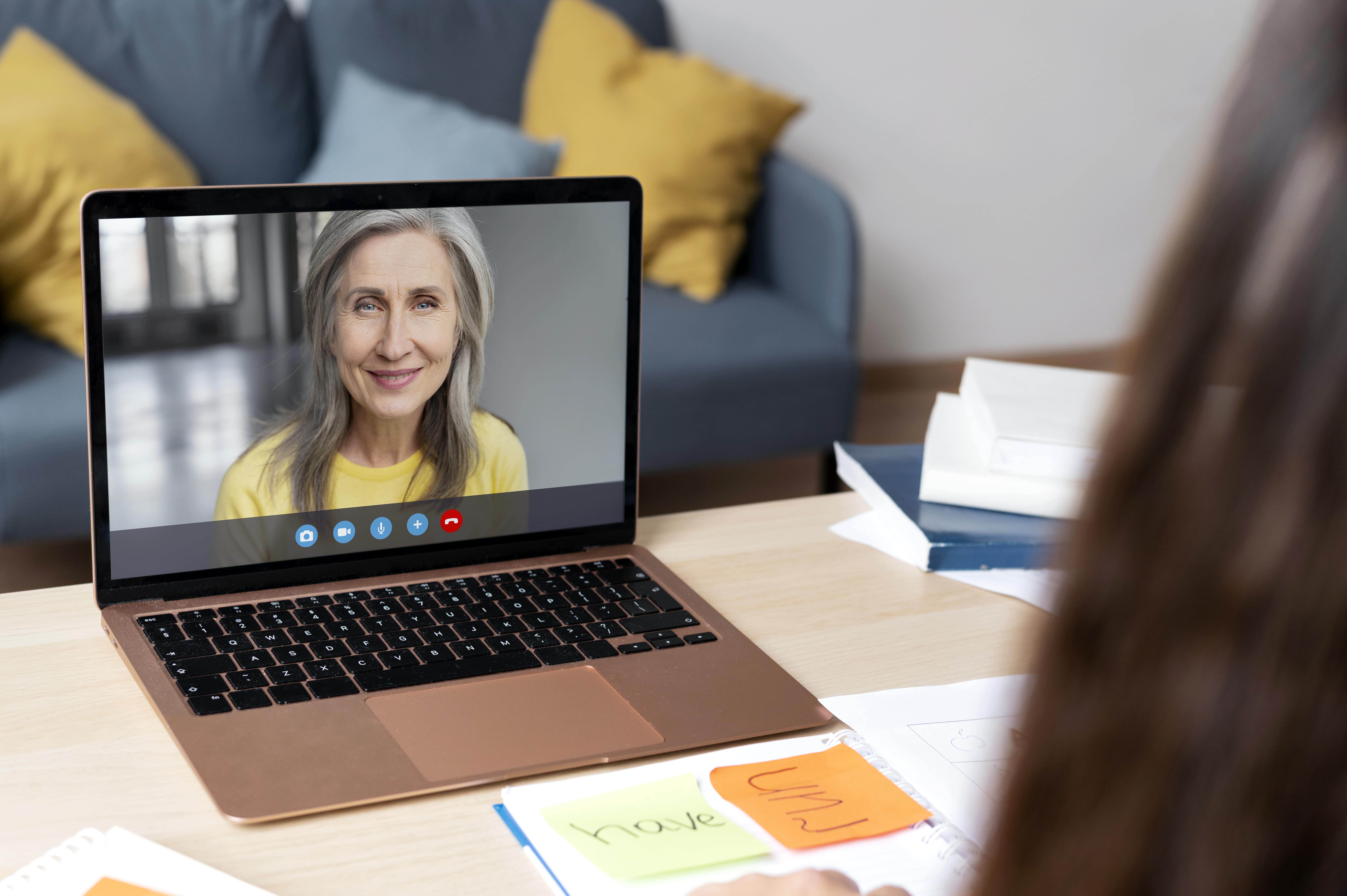 Ältere Frau lächelt während eines Videoanrufs auf einem Laptop.