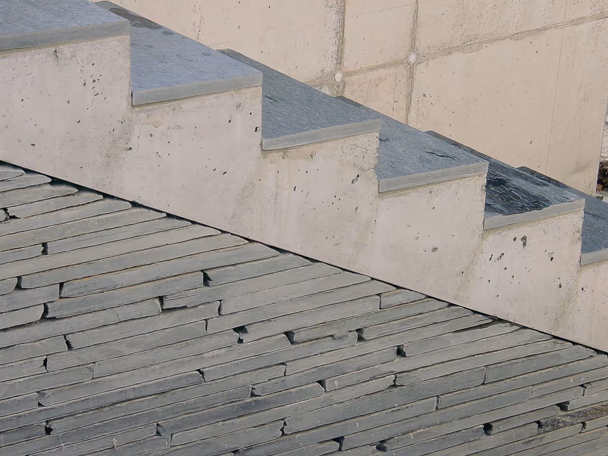 Moderne Betontreppe mit strukturierter Steinmauer