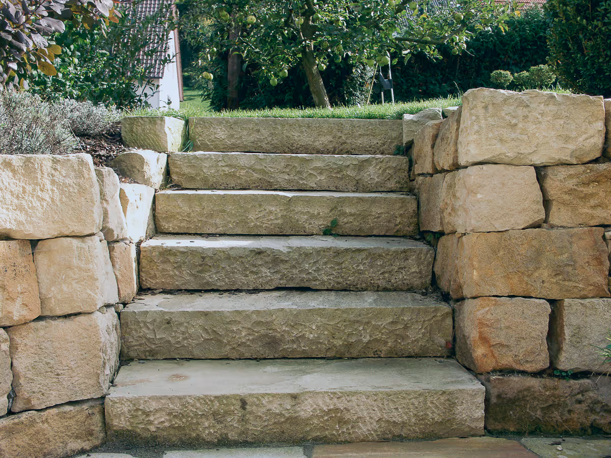Natursteintreppe im Garten mit rustikalen Sandsteinblöcken und Grünanlagen