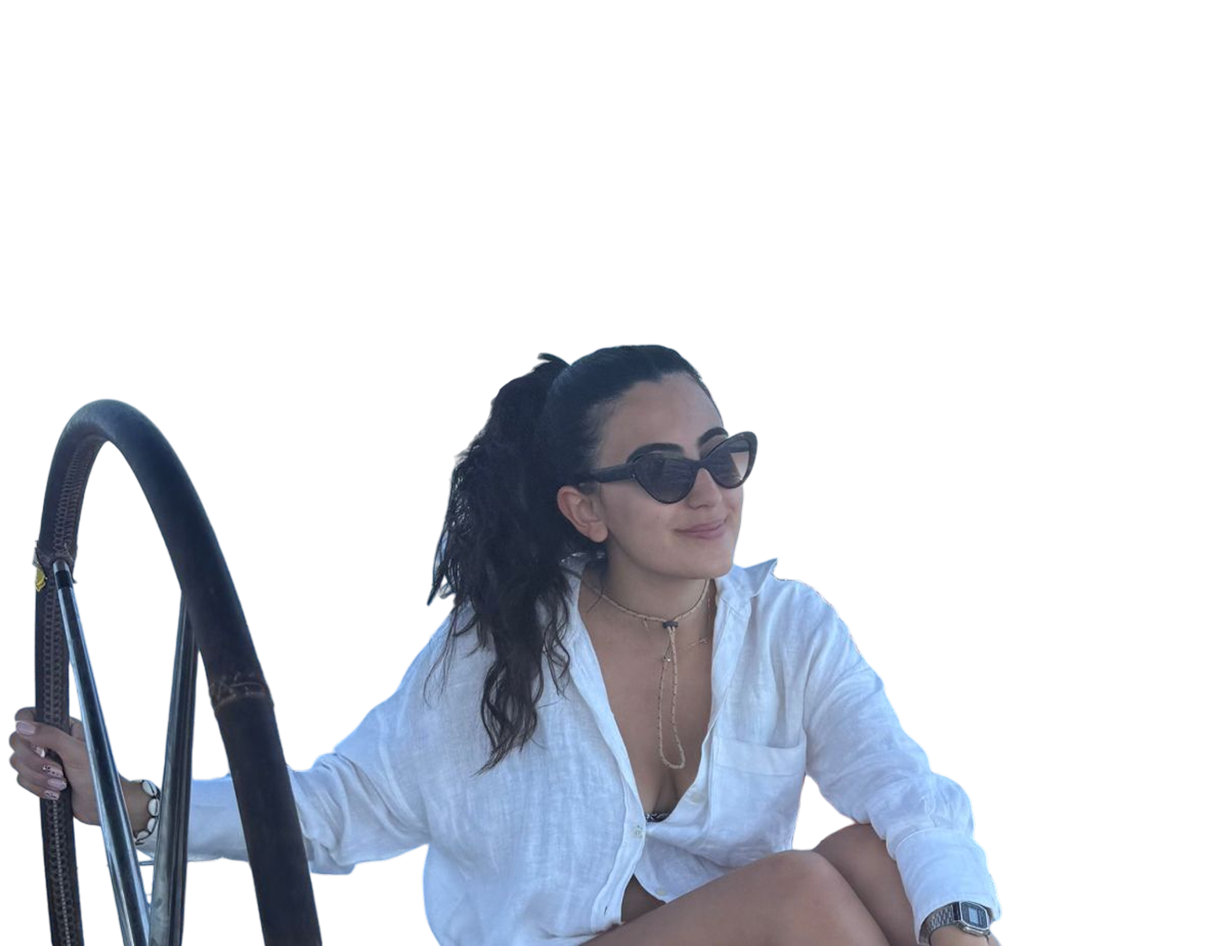 Woman with long dark hair in a ponytail wearing black cat-eye sunglasses and a white button-up shirt, holding a boat railing and smiling.