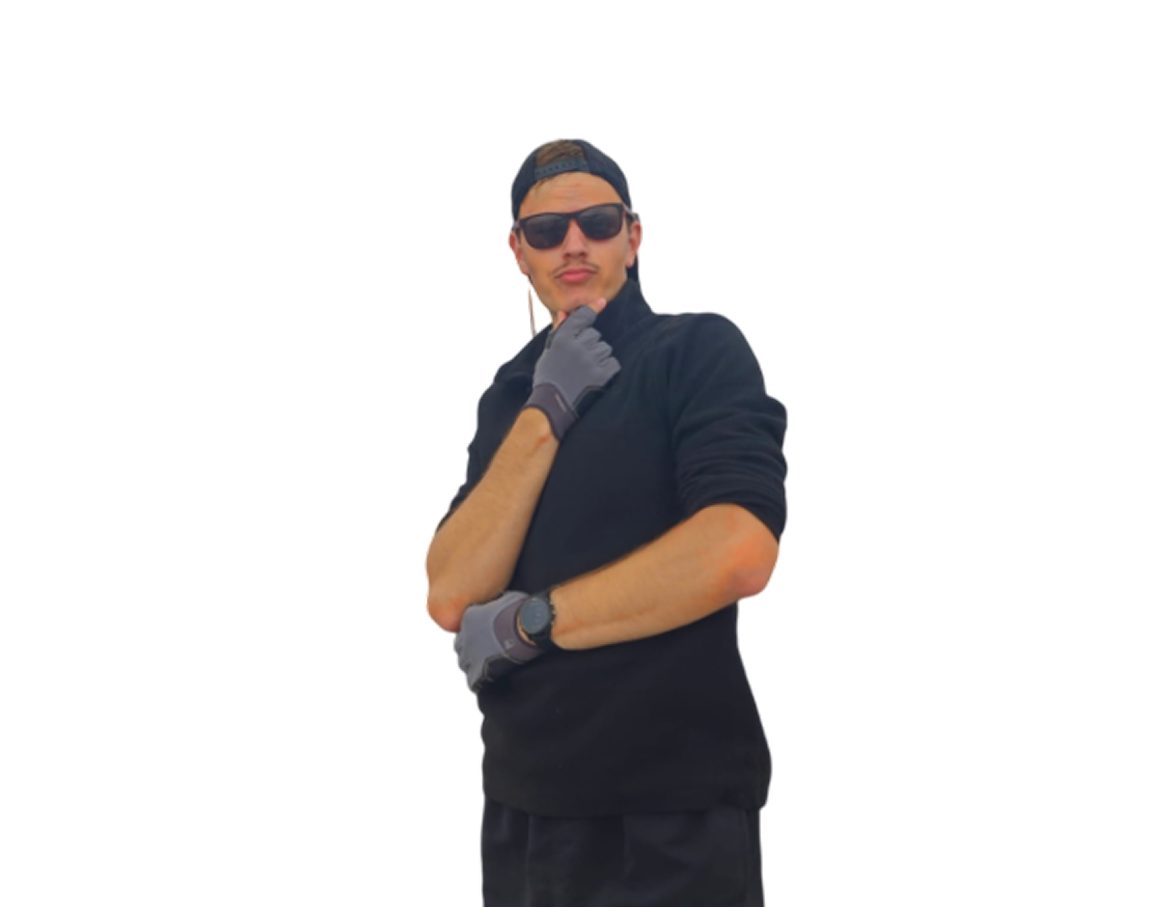 Man wearing black sunglasses, black cap backwards, black long-sleeve top, and gray gloves posing with one hand on chin and the other crossed.