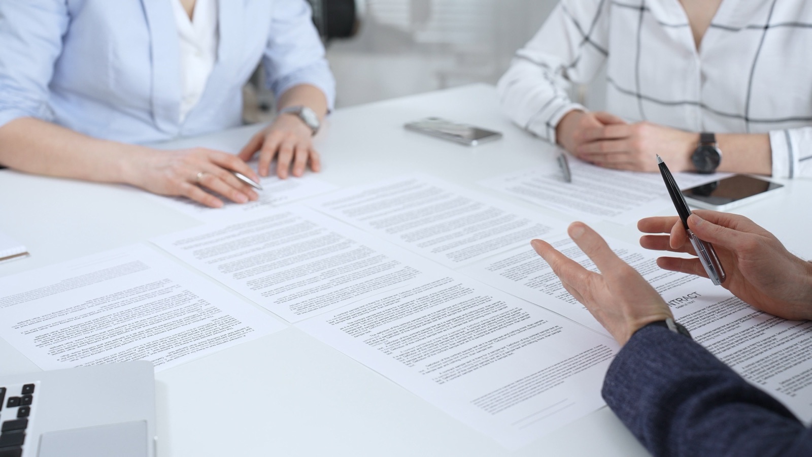 Échange autour de documents contractuels posés sur une table de réunion