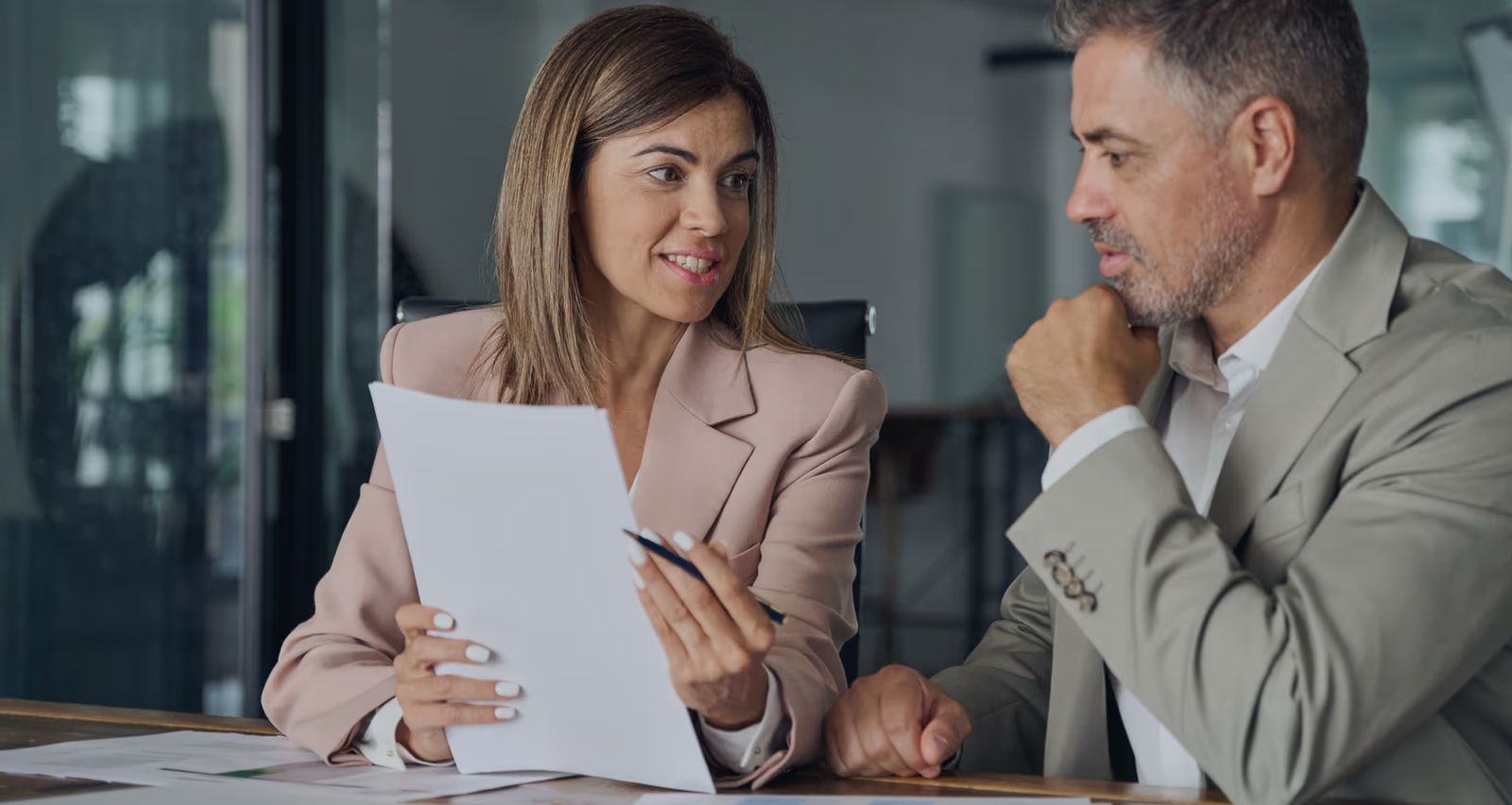 Deux professionnels échangent autour d’un document lors d’une réunion de travail