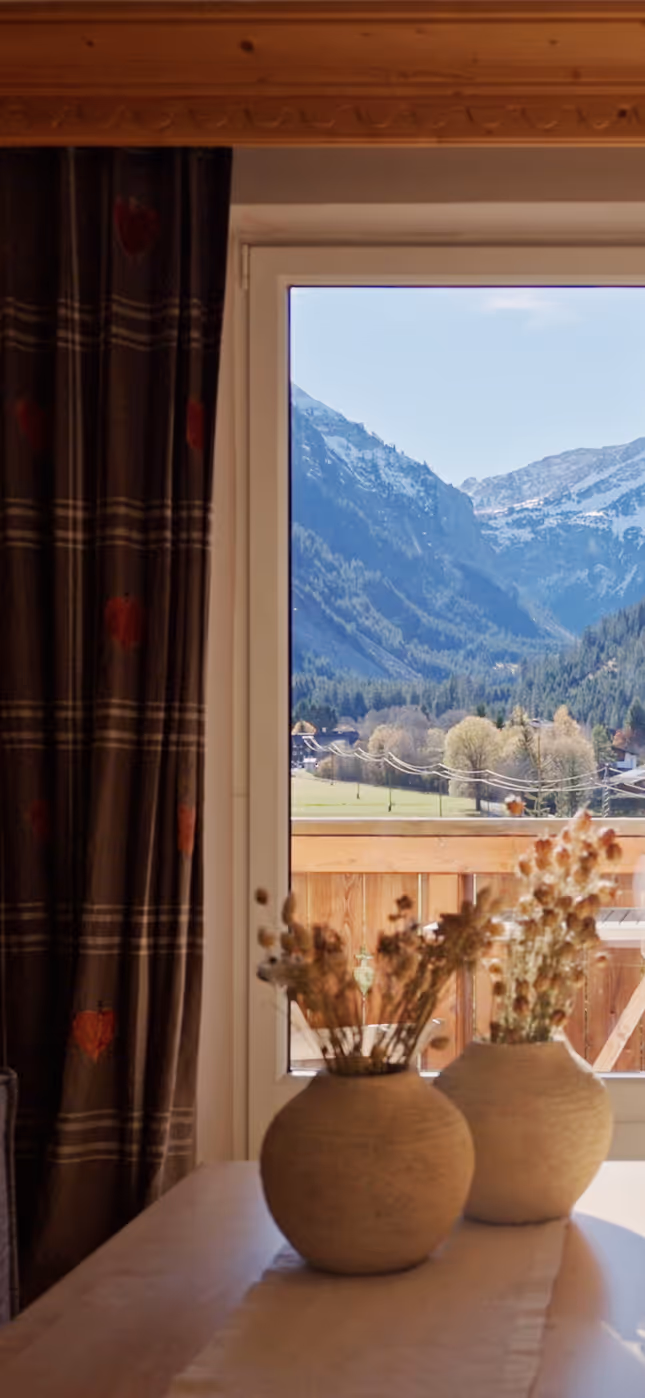 Ausblick aus dem Zimmer des Hotel Hohenfels auf das Tannheimer Tal – Morgensonne und Bergpanorama.
