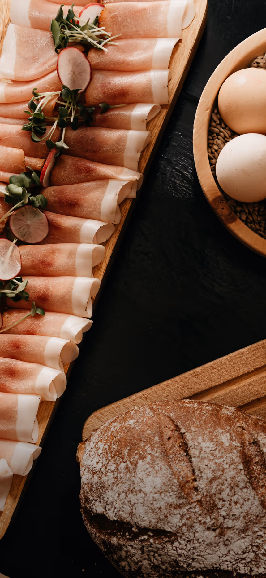 Regionale Frühstücksauswahl im Hotel Hohenfels Tirol mit frischem Brot, Eiern und Schinken – Genuss am Morgen.