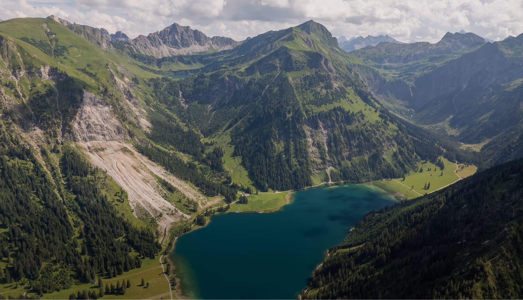 Luftaufnahme des Vilsalpsees im Tannheimer Tal umgeben von grünen Bergen.