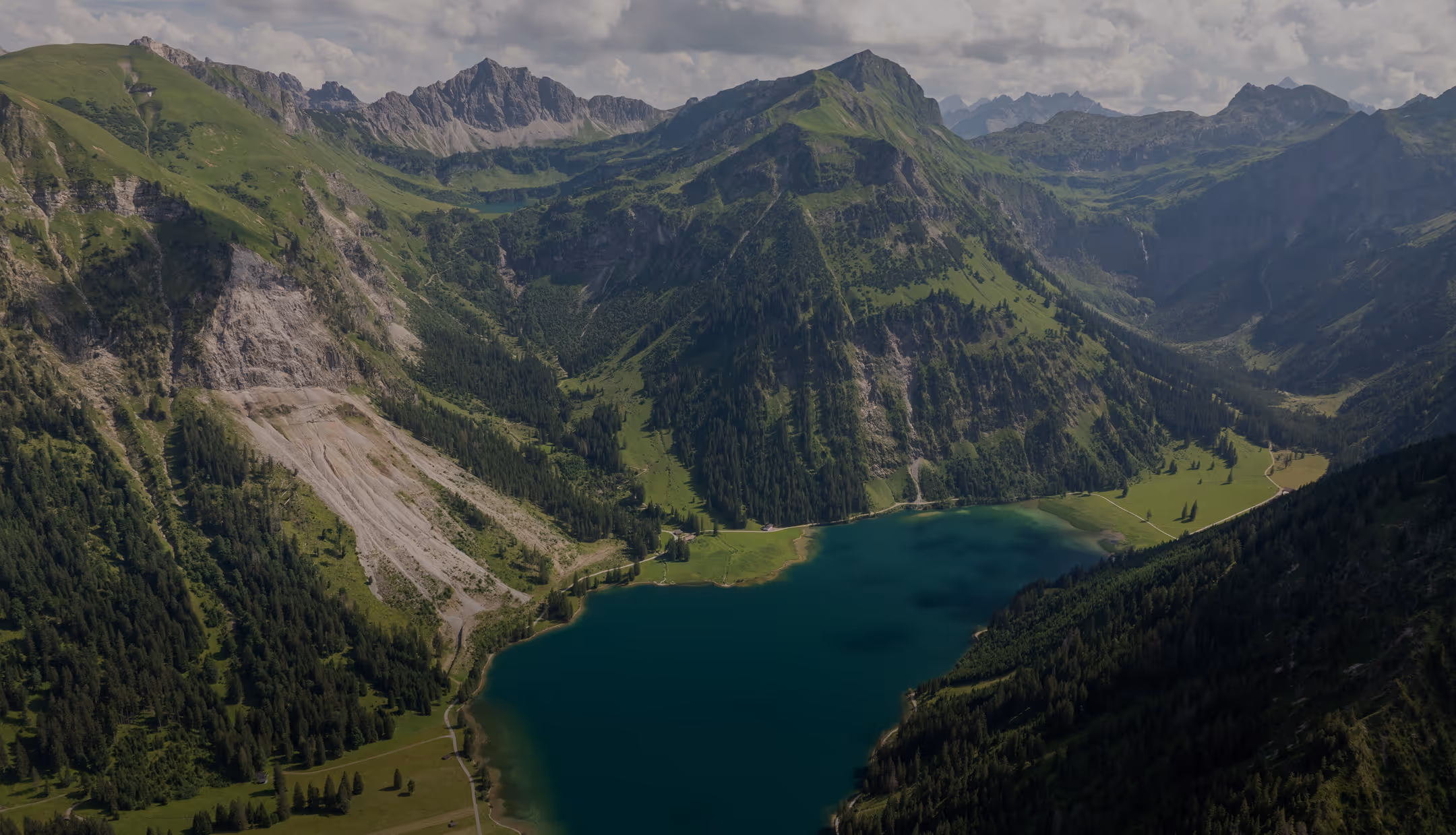 Luftaufnahme des Vilsalpsees im Tannheimer Tal umgeben von grünen Bergen.