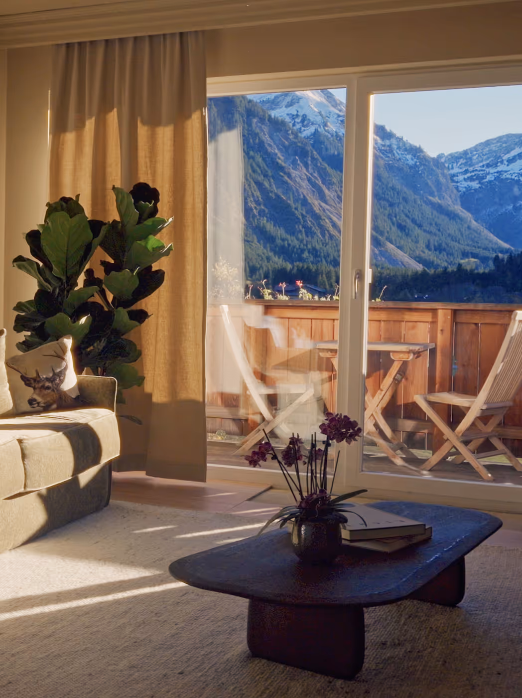 Gemütliches Zimmer im Hotel Hohenfels mit Sofa, Holzelementen und Balkonblick auf die Tiroler Berge.