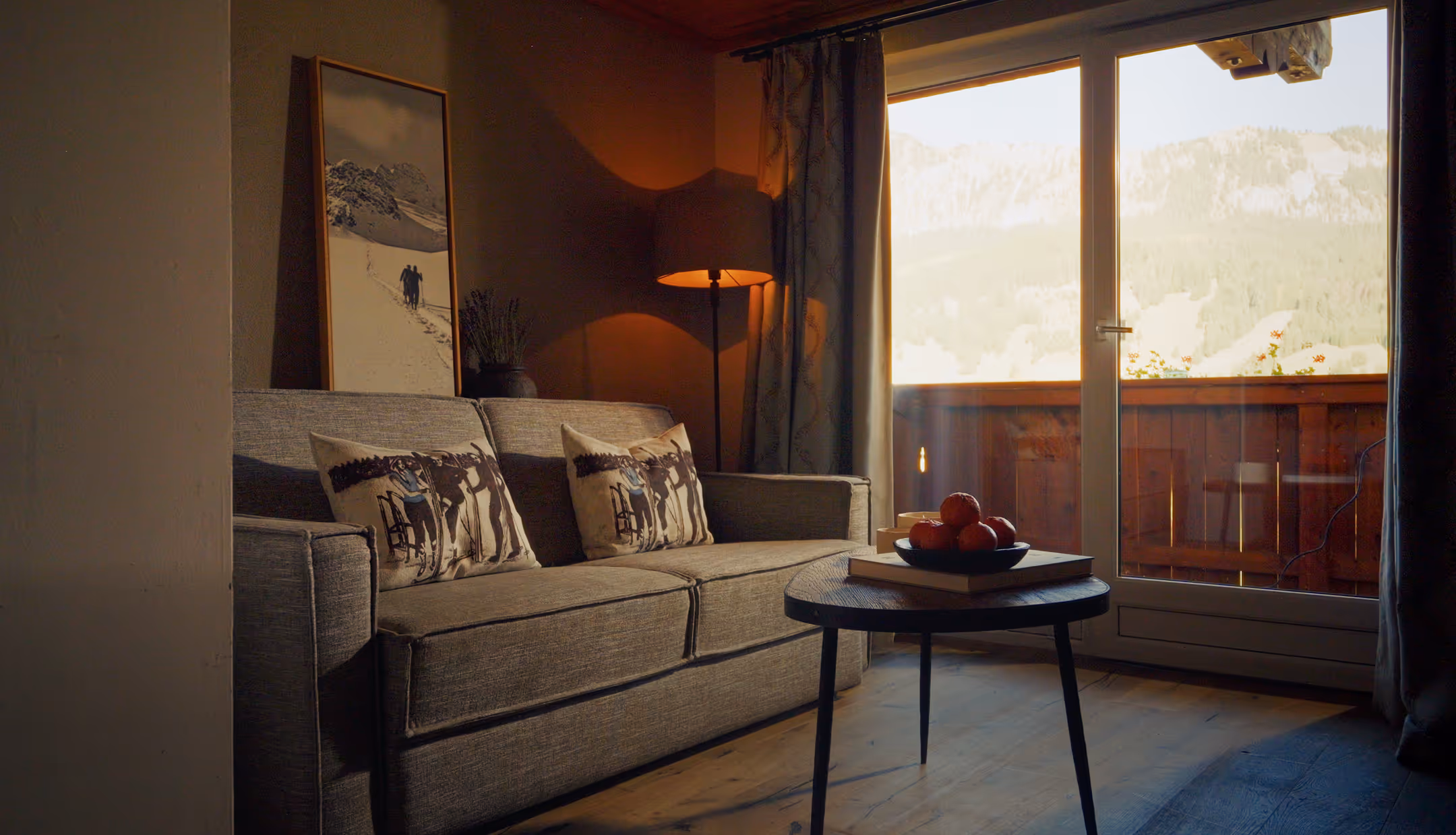 Suite Silberdistel mit grauem Sofa, Balkon und Bergblick – stilvolle Wohlfühlatmosphäre im Hotel Hohenfels Tirol.
