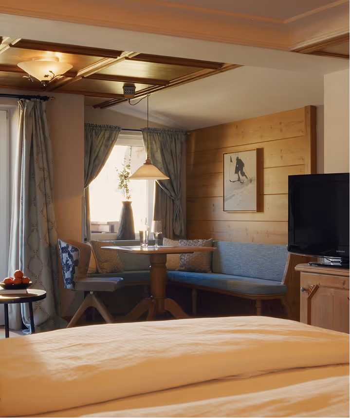 Suite Silberdistel mit heller Sitzecke, Vorhängen in Pastelltönen und traditionellem Tiroler Charme.