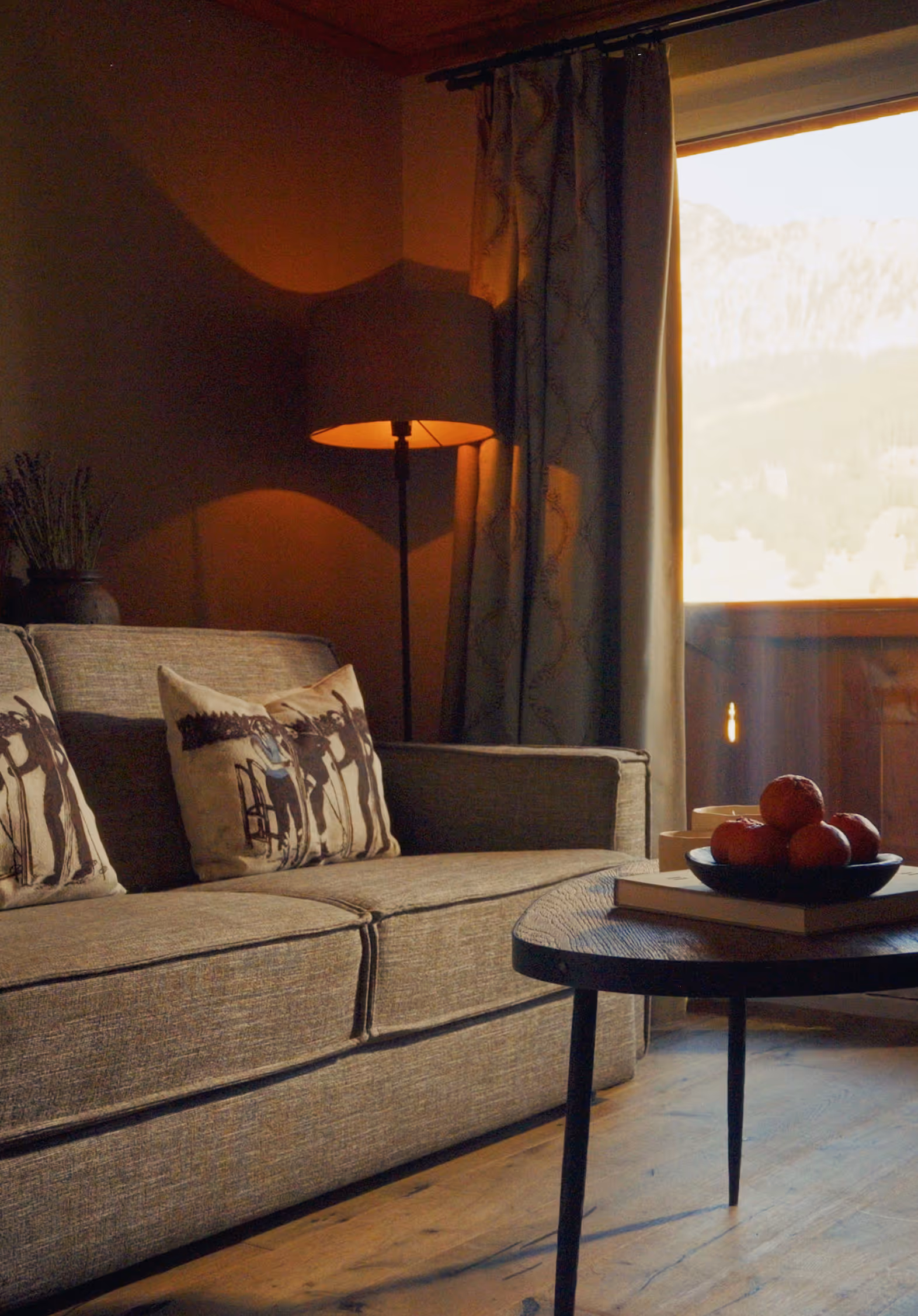 Detailaufnahme der Suite Silberdistel: gemütliches Sofa mit Hirschkissen, Couchtisch und Ausblick auf die Berge.