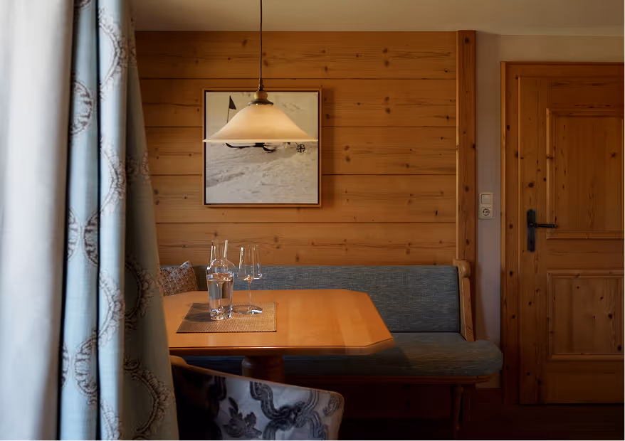 Gemütlicher Essbereich der Suite Silberdistel mit Holzwand, Pendelleuchte und stilvoller Sitzecke im Hotel Hohenfels Tirol.