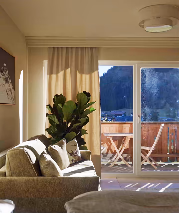 Heller Wohnbereich der Suite Vilsalpsee mit großem Fenster, Alpenblick und sanfter Nachmittagssonne.