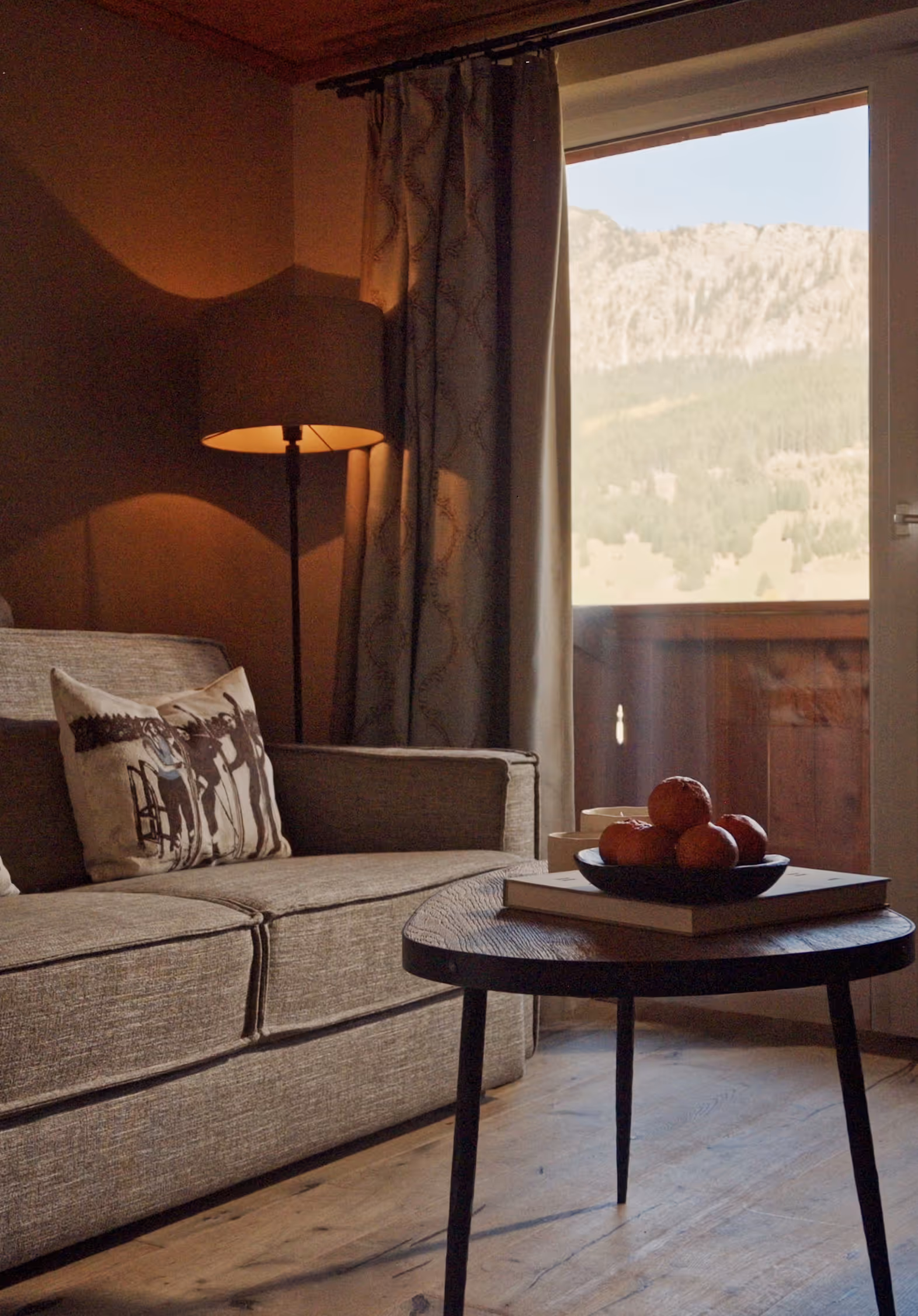 Suite Silberdistel mit grauem Sofa, Balkon und Bergblick – stilvolle Wohlfühlatmosphäre im Hotel Hohenfels Tirol.