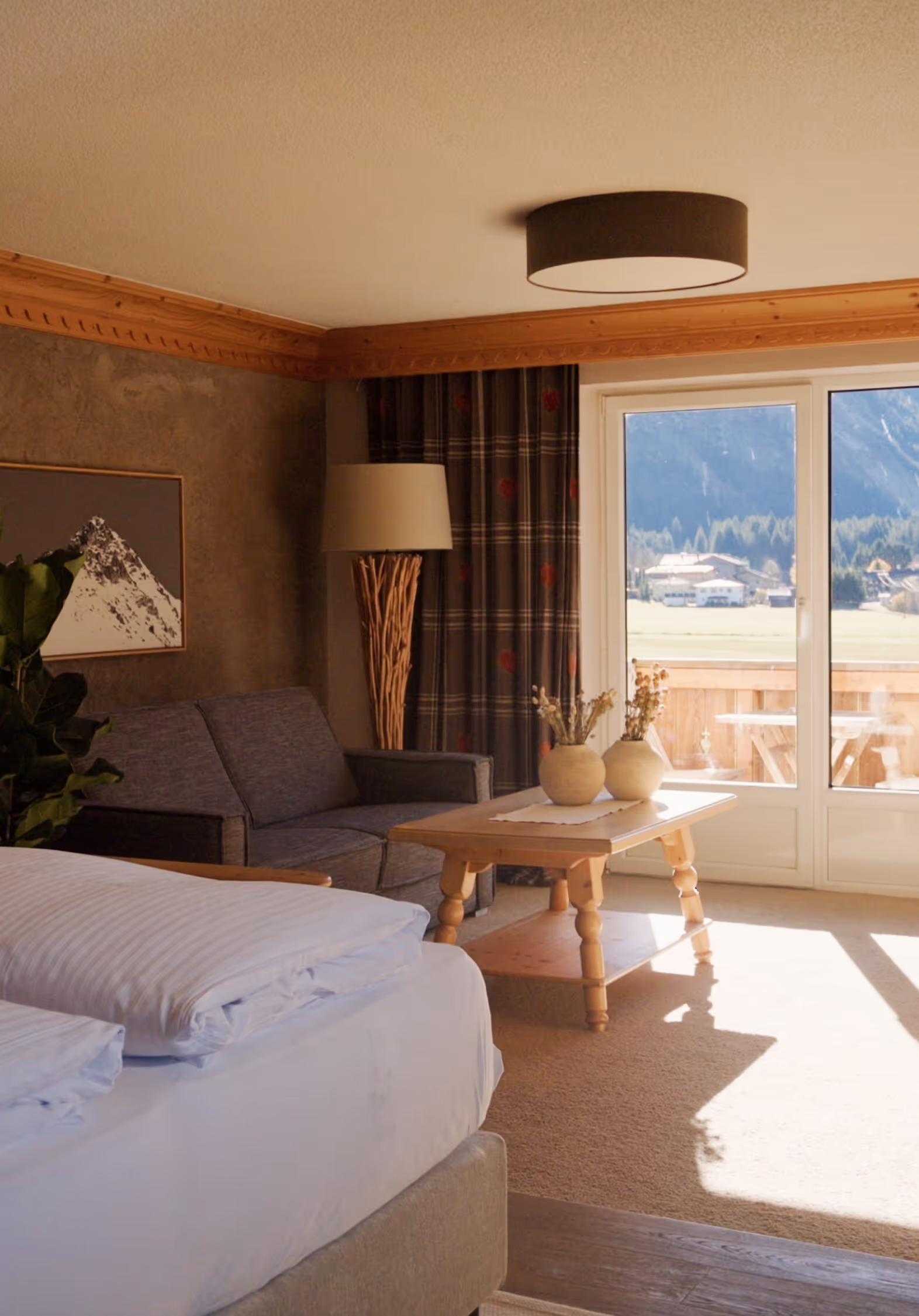 Helle Suite Vergissmeinnicht im Hotel Hohenfels mit Holzmöbeln, gemütlichem Bett und Balkonblick auf die Tiroler Bergwelt.
