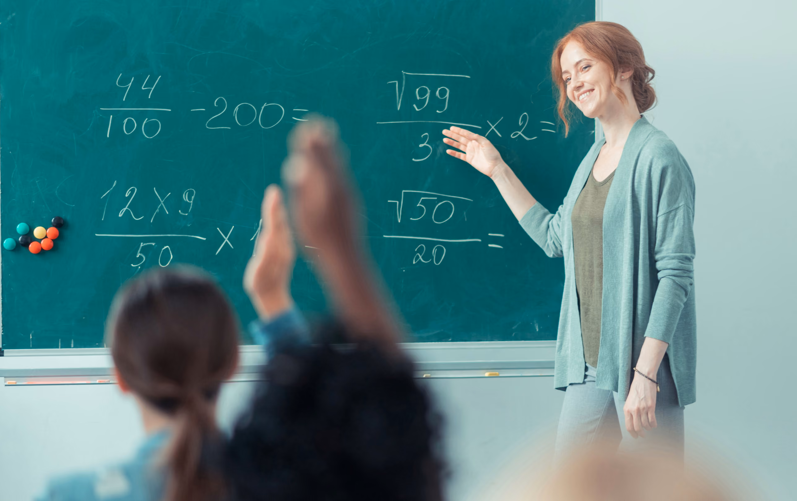 a teacher points to a chalkboard