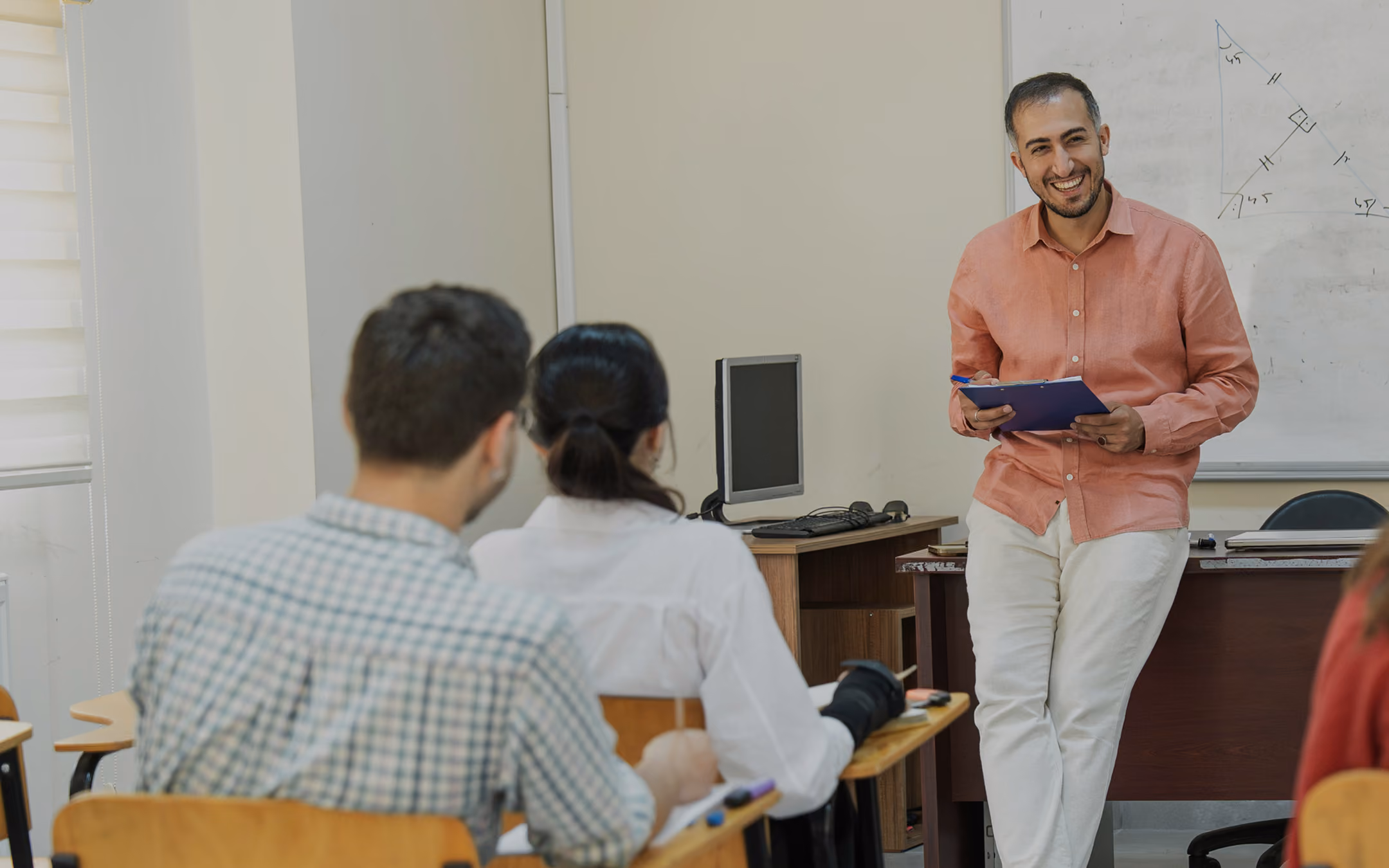 a teacher leans on a desk