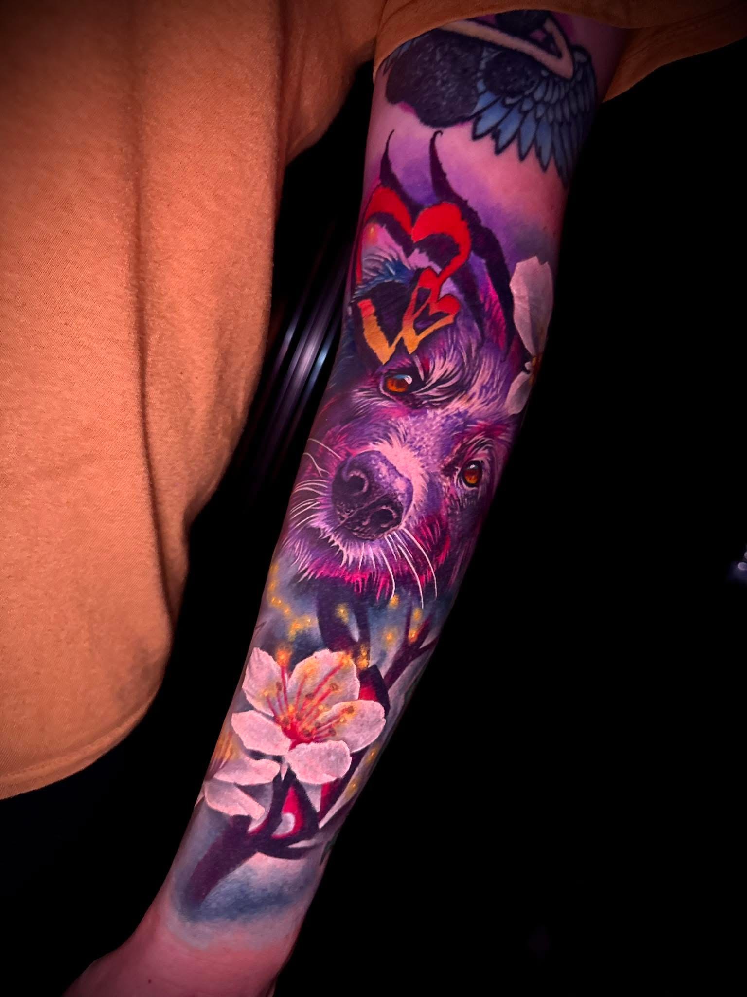 Colorful tattoo on forearm featuring dog pet portrait.
