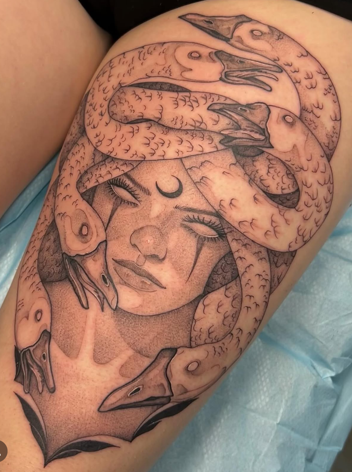 Fine line tattoo Medusa, a crescent moon on her forehead, tears, and multiple goose heads intertwined around her head.