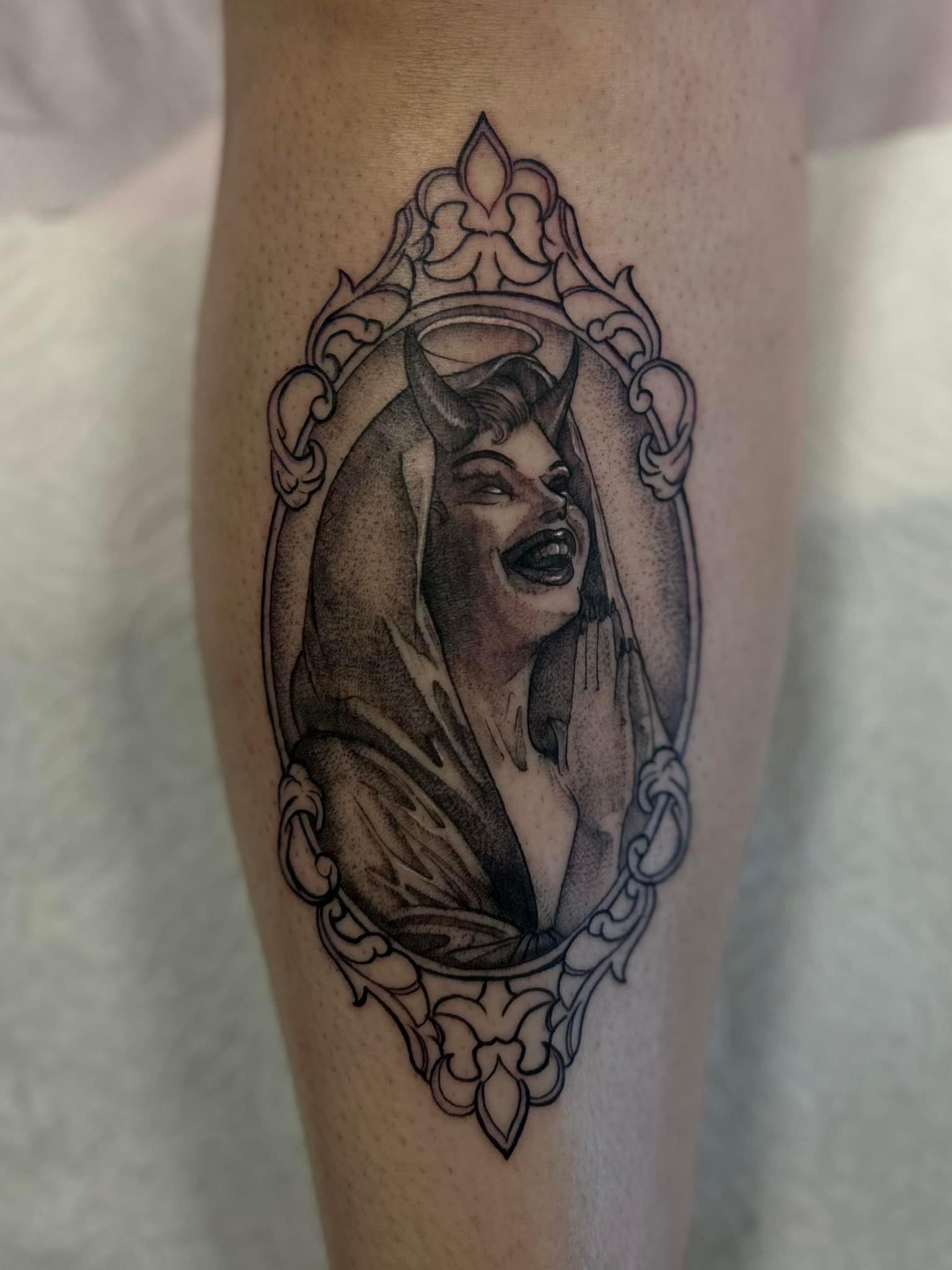 Fine line tattoo of a praying woman with devil horns and a halo, framed with ornate decorative border.