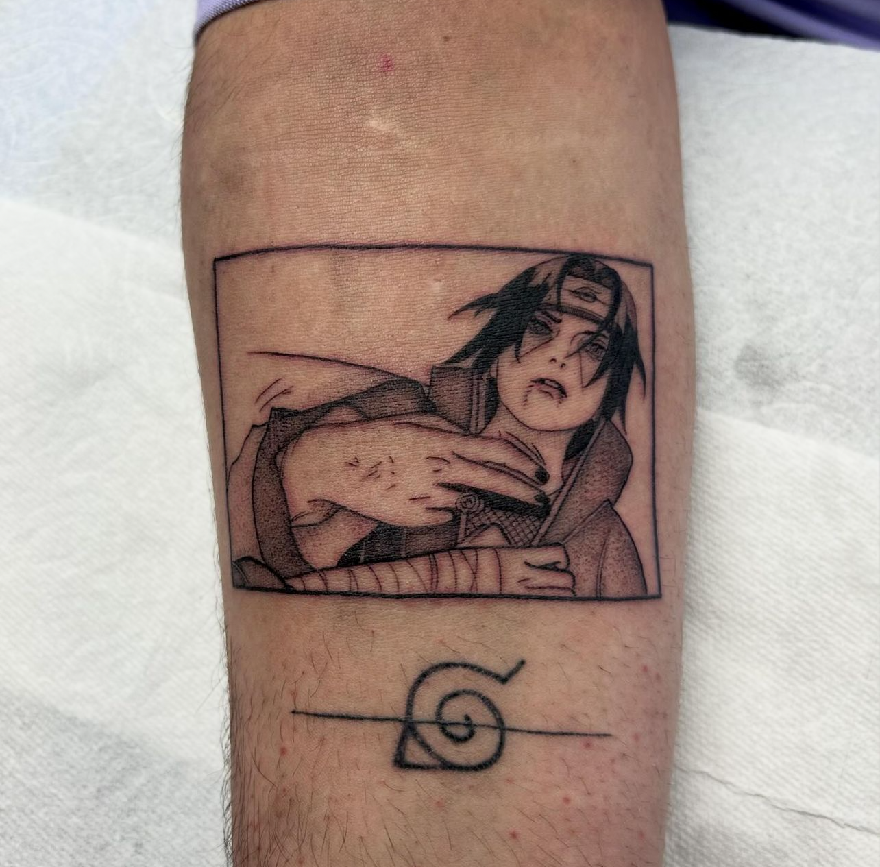 Tattoo of anime character Itachi Uchiha from Naruto with Sharingan symbol below.