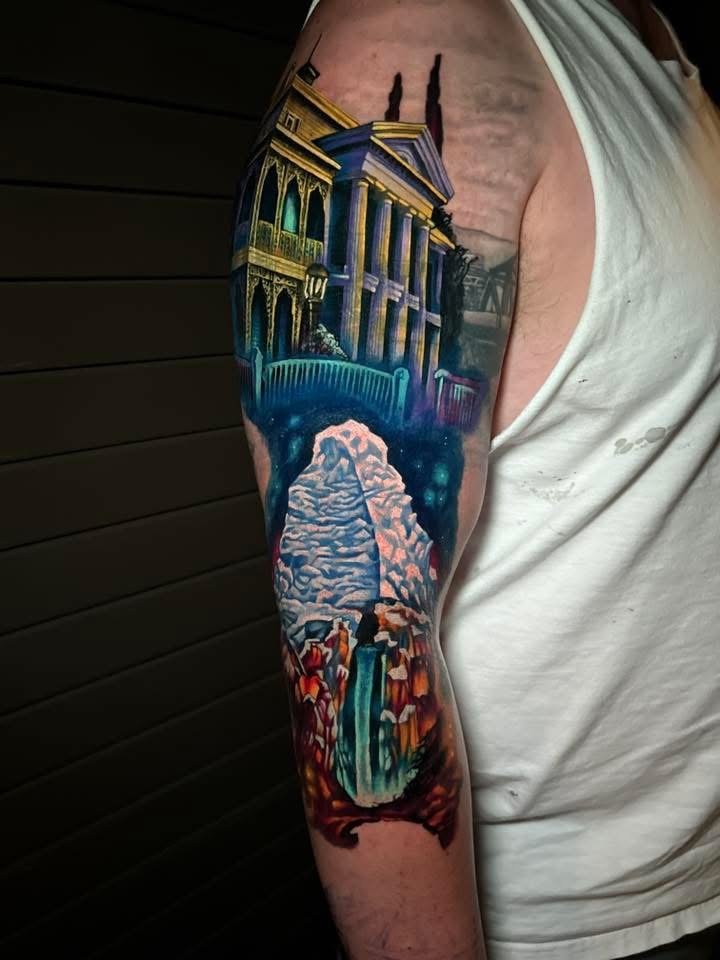 Colorful tattoo on upper arm featuring Disney's Haunted Mansion.