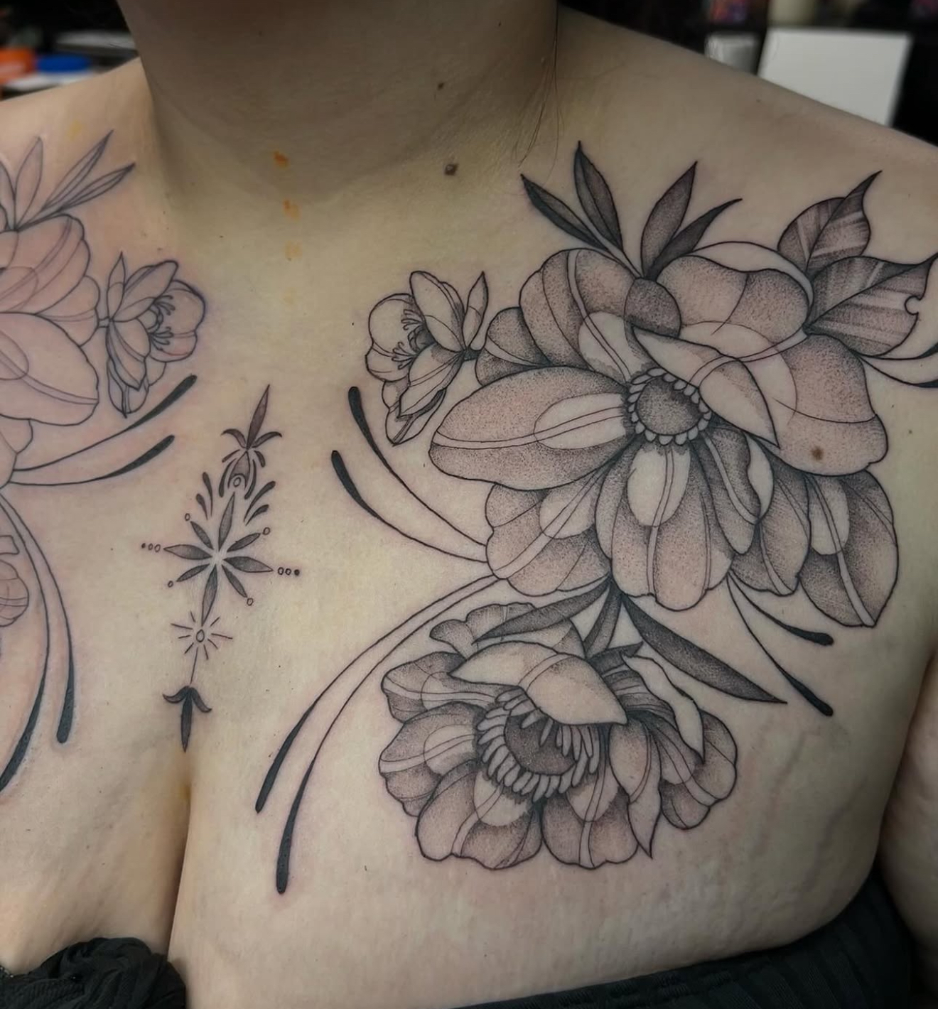 Fine line black and gray tattoo of large flowers chest piece