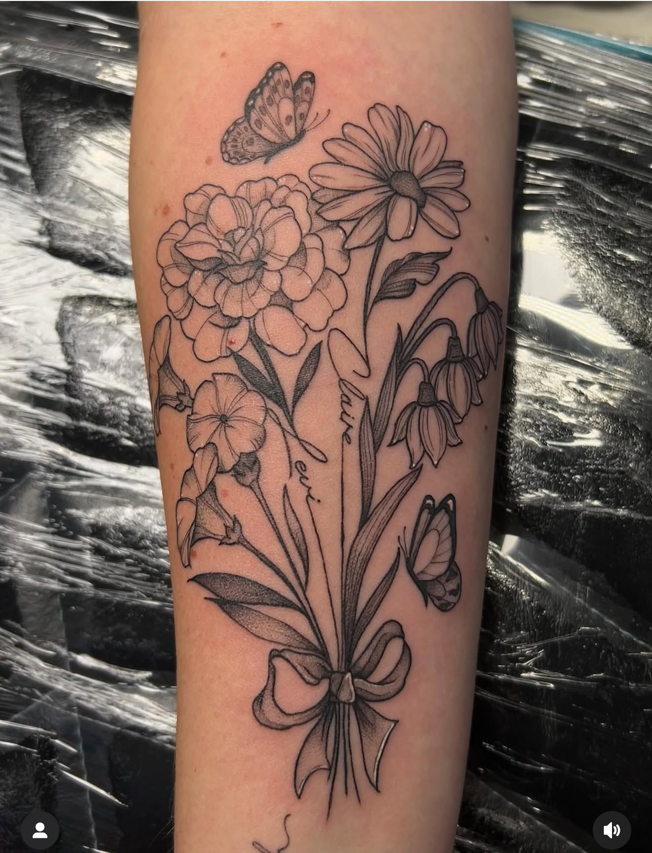 Fine line black and grey tattoo of a bouquet of various flowers tied with a ribbon