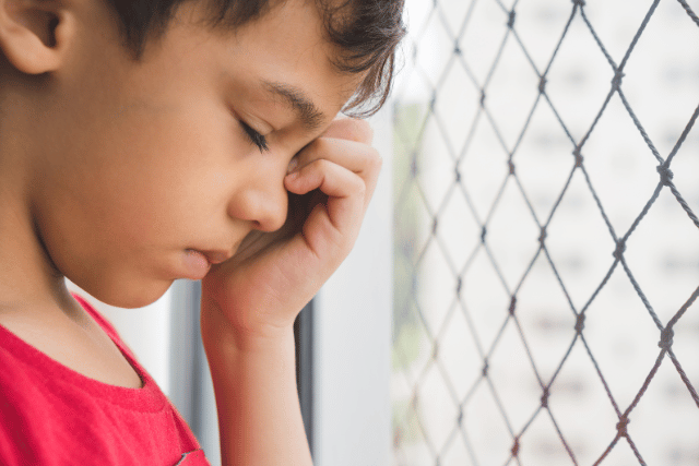 niño somnoliento con la mano en la cara
