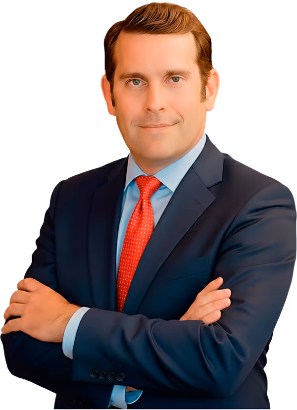 Confident man in a dark suit and red tie standing with arms crossed.