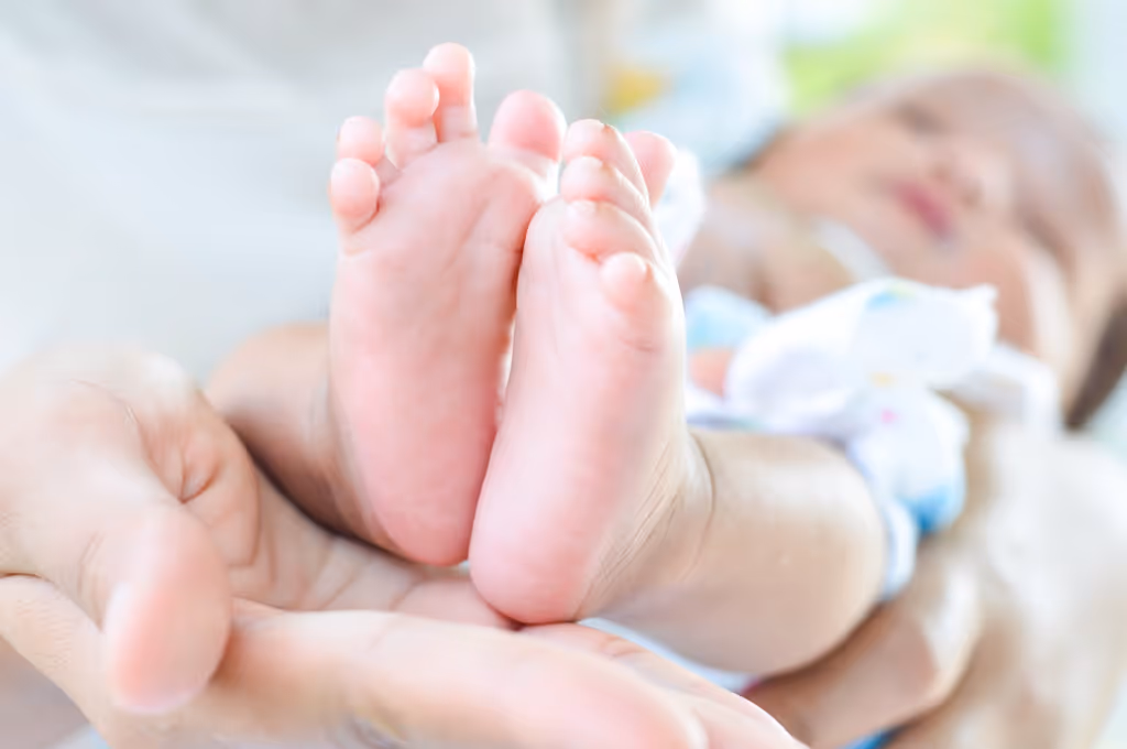 Close-up of an adult hand gently holding a baby's feet.