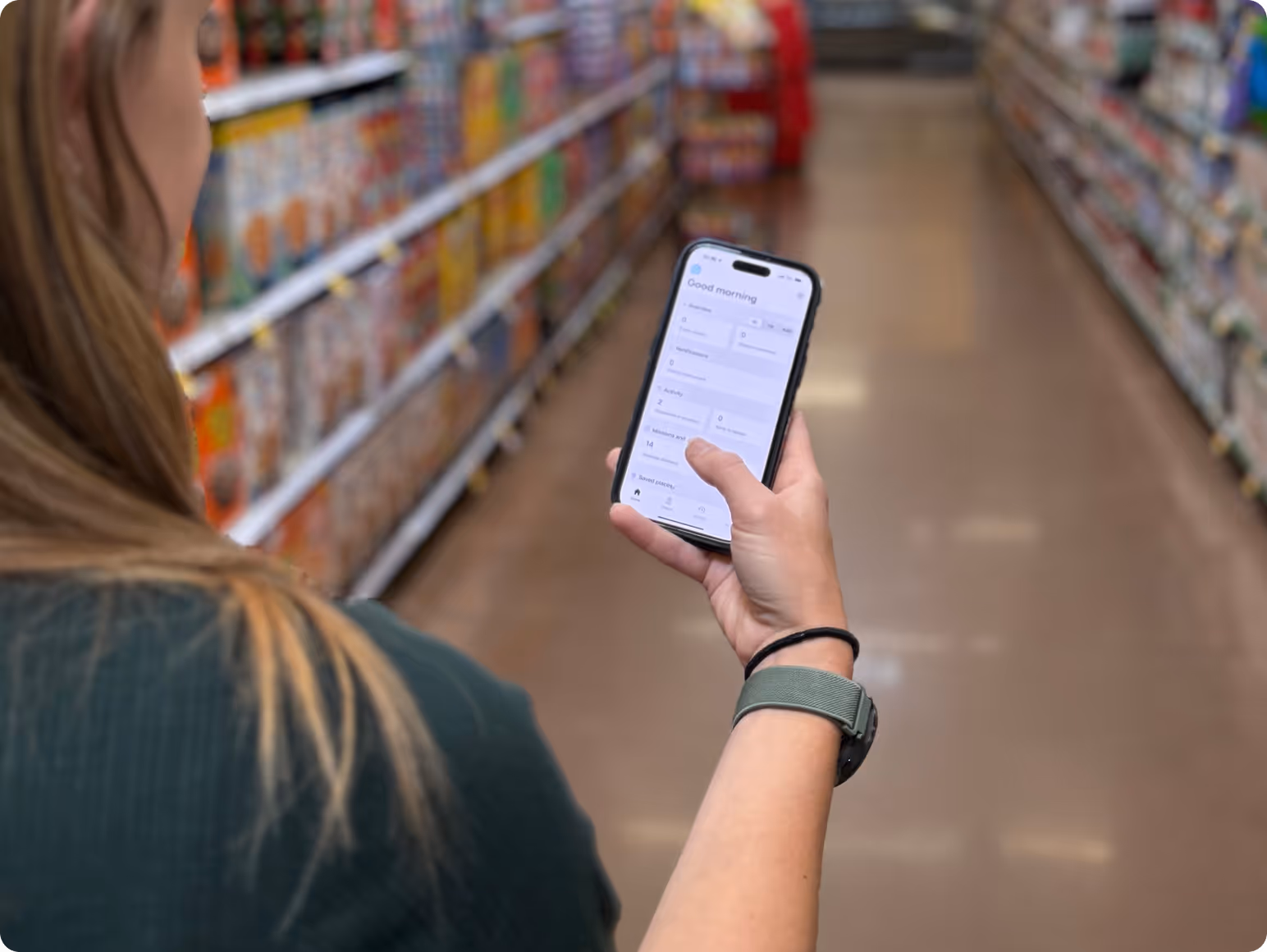 Person holding a smartphone with a productivity app open while standing in a grocery store aisle.