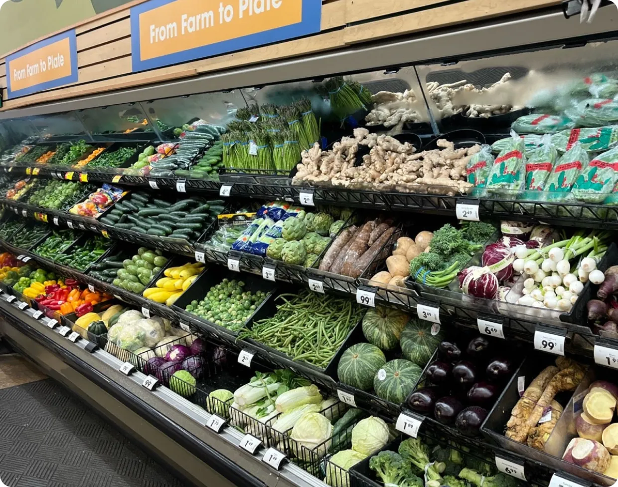 Supermarket display of fresh vegetables and produce under signs reading From Farm to Plate.