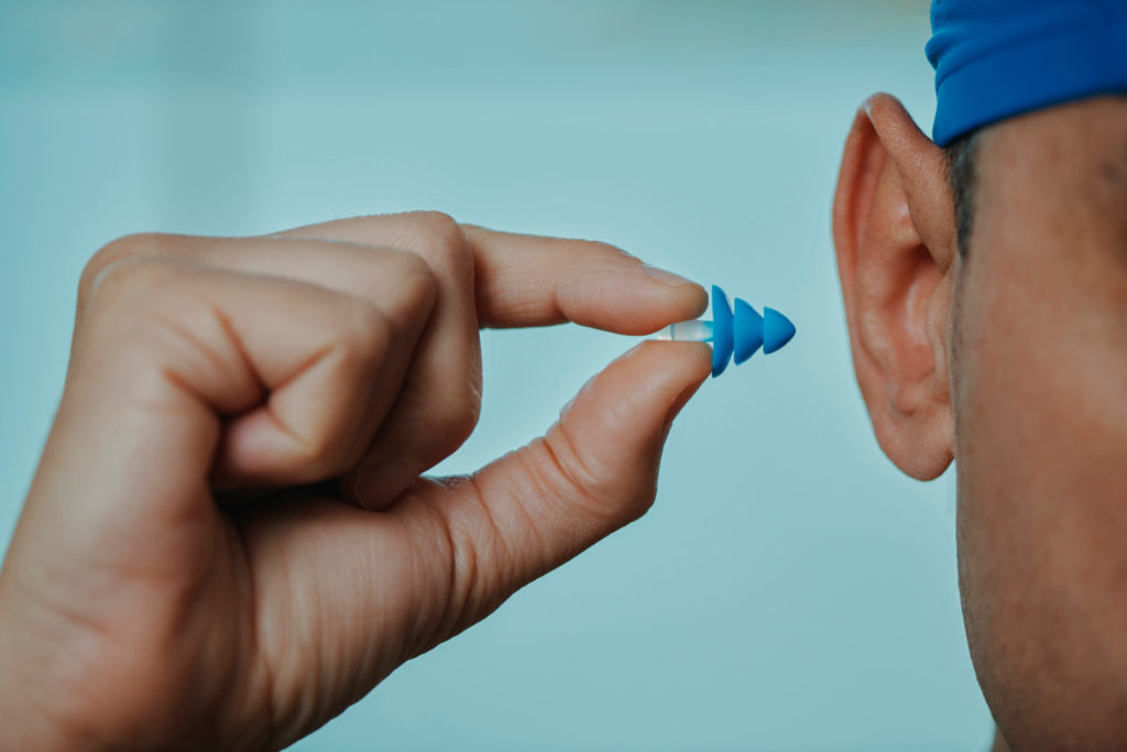 man placing custom swimming ear plug in his ear