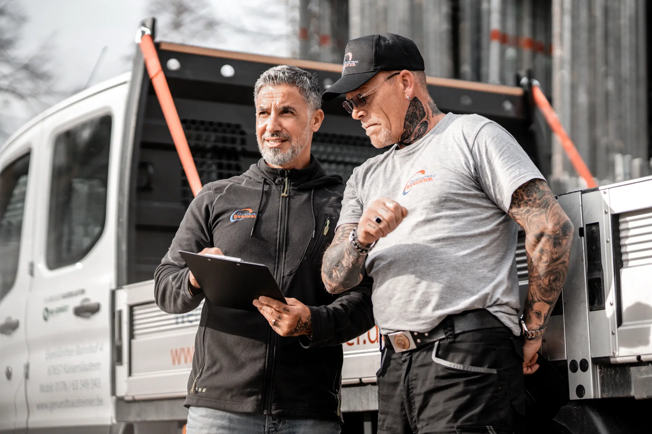 beide Geschäftsführer stehen vor einem Fahrzeug