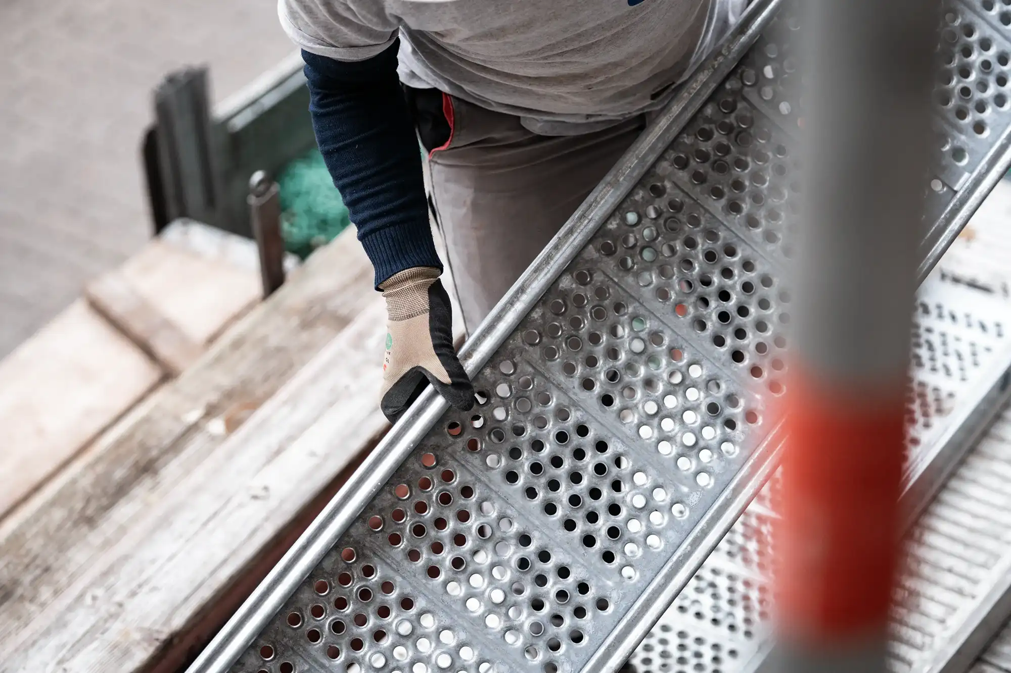 Gerüstbau Steiner Arbeiter trägt Bodenplatte