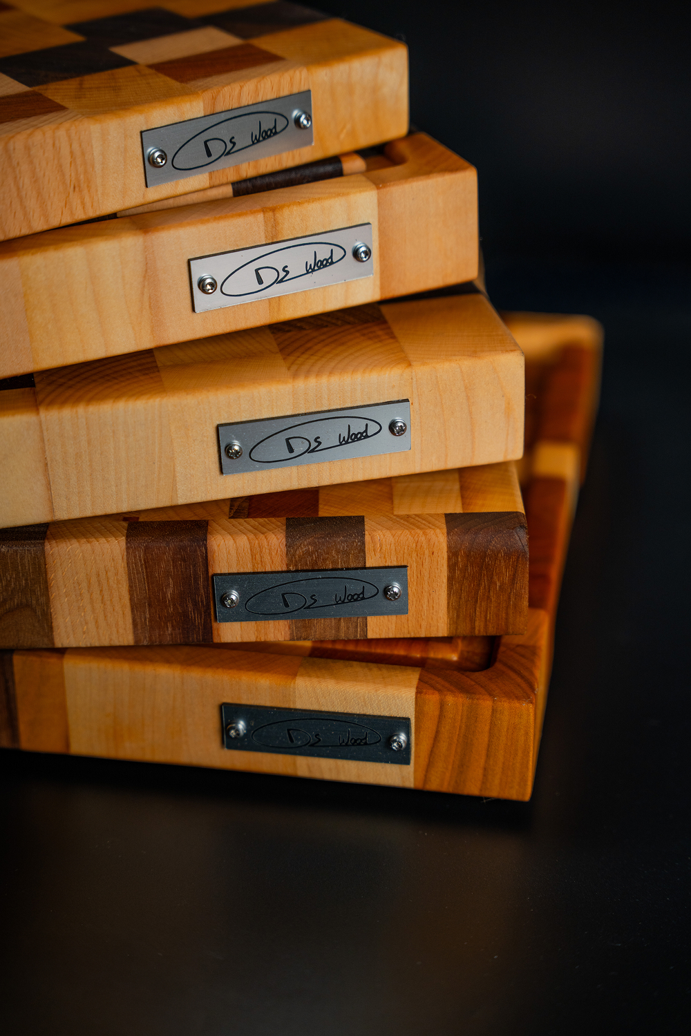 Piles de planches à découper en bois avec des plaques métalliques portant l'inscription Ds Wood.