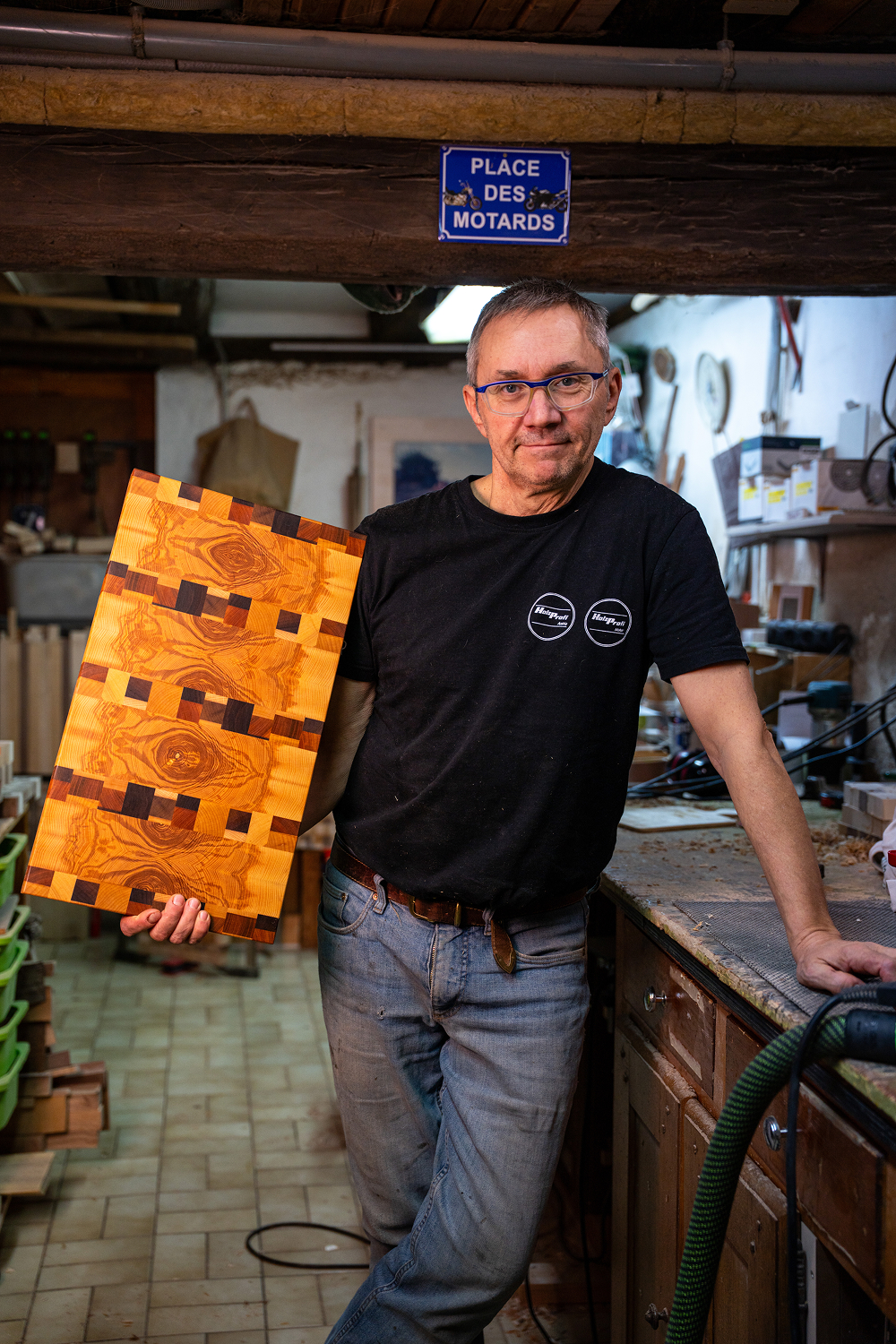 Homme tenant une planche à découper en bois finement travaillée dans un atelier de menuiserie.