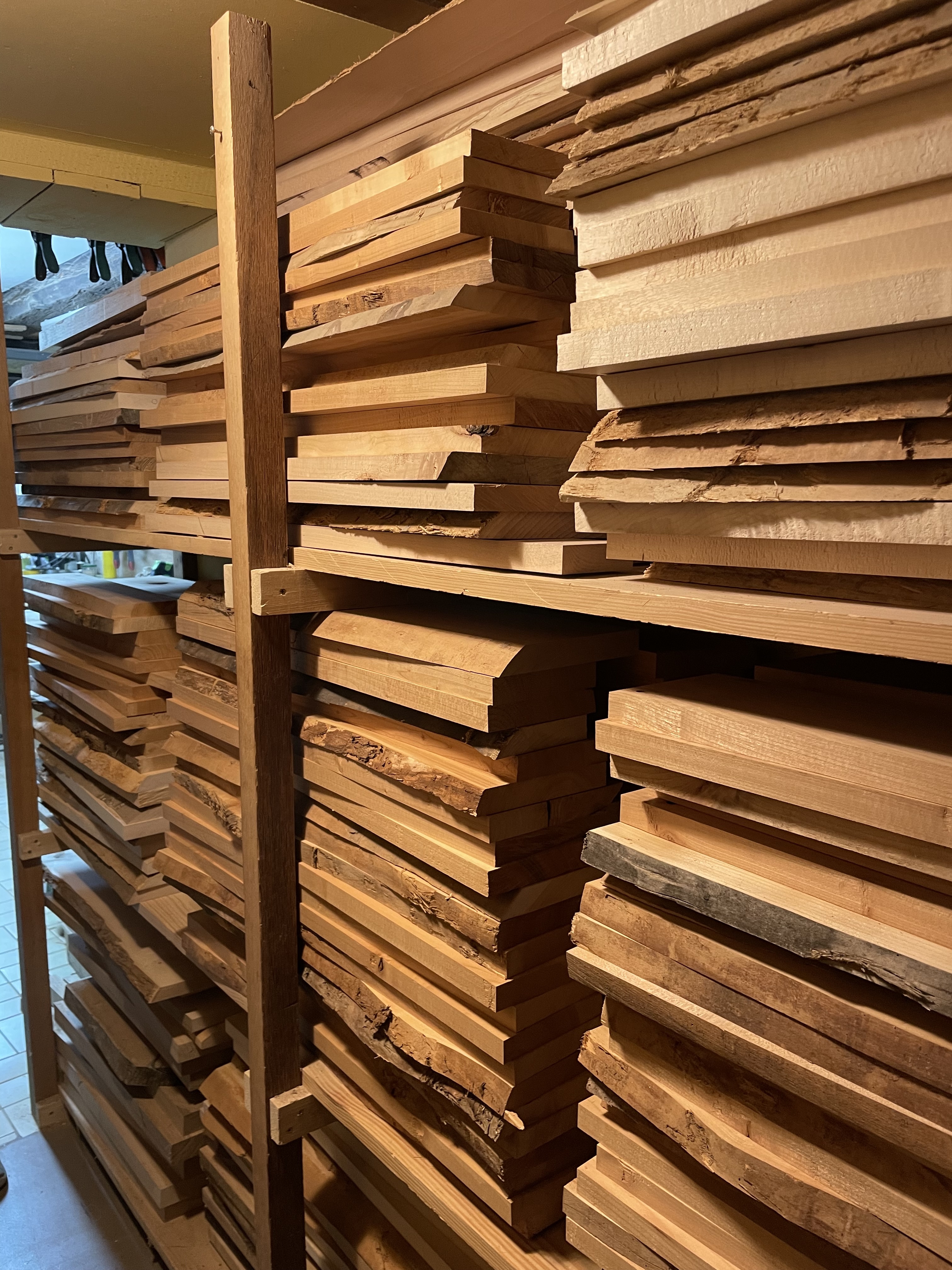 Pile de planches de bois empilées sur des étagères en bois dans un atelier.