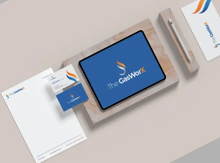 Branding set for The GasWorx featuring a tablet displaying the logo, business cards, letterhead, and a pen on a beige background.